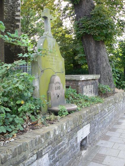 Stone in graveyard surmounted with cross, with inscription