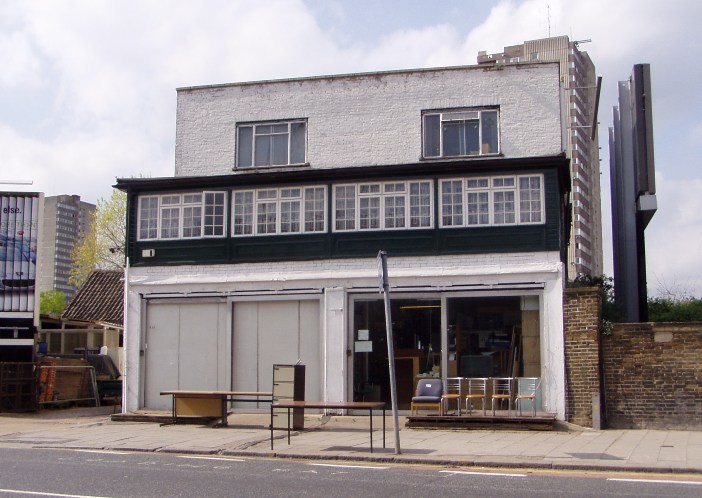 Two semi-detached white painted shops with a few chairs and tables on the pavement in front