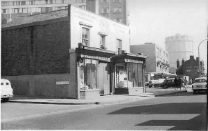 Small island of three shops with new buildings looming behind